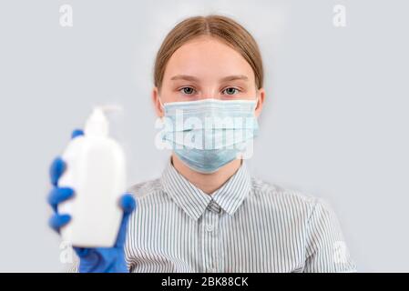 Adolescente ragazza, maschera medica copre il suo viso, tiene la mano antisettica, sapone liquido, sfondo bianco, assistenza cura ricordare ai pazienti circa la sicurezza, COVID-19 Foto Stock