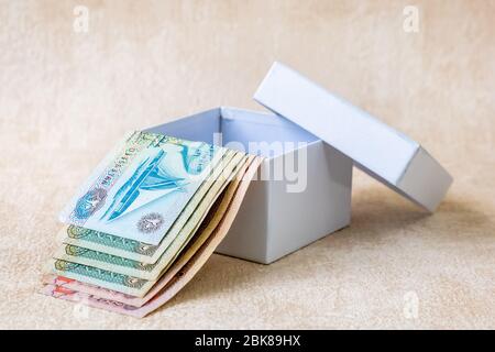 Molte banconote della banca di Dirham degli Emirati Arabi Uniti, soldi arabi nella scatola bianca del regalo. Studio. Foto Stock