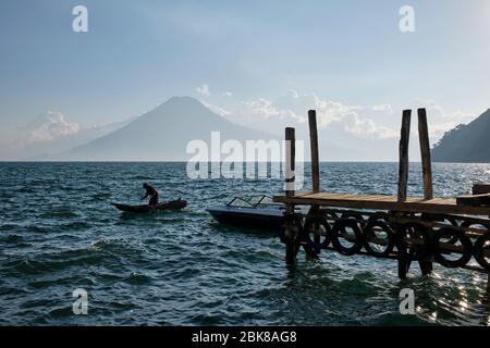 Pescatore in una piccola barca di pesca nel lago Atitlan con vista sul vulcano Atitlan sullo sfondo. Foto Stock