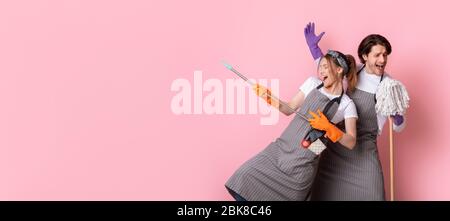 Coppia di janitors che si divertono durante la pulizia, ingannando con mop e scopa Foto Stock