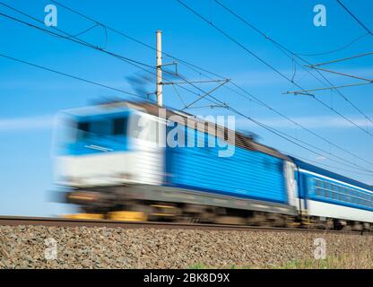 Il treno blu alimentato dall'elettricità, attraversa la campagna. Sfocato Foto Stock