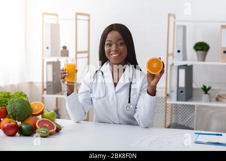 Donna africana dietista che raccomanda succo d'arancia fresco Foto Stock