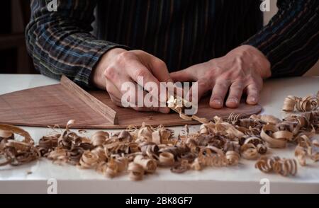 un maschio liutaio, strumento musicale creatore di bretelle piramiding sul lato posteriore della chitarra / ad alta voce Foto Stock