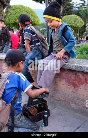 Shoe Shine boy pulizia scarpe da ragazzo nella piazza principale di Nebaj. Foto Stock