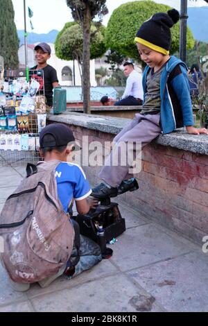 Shoe Shine boy pulizia scarpe da ragazzo nella piazza principale di Nebaj. Foto Stock