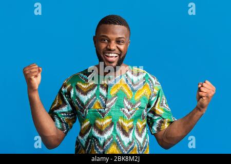 Uomo nero emozionale in camicia colorata che esprime la felicità Foto Stock