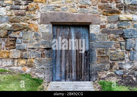 Vecchia porta in legno posta in un muro di pietra di un castello Foto Stock