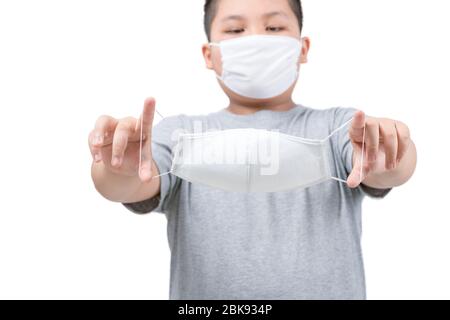 Ragazzo grasso che tiene maschera chirurgica medica in mani isolate su sfondo bianco. Influenza, malattia, misure preventive contro l'infezione da Covid-19. Concetto di Foto Stock