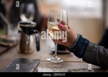 Bicchiere di vino bianco tenuto in mano alla donna Foto Stock