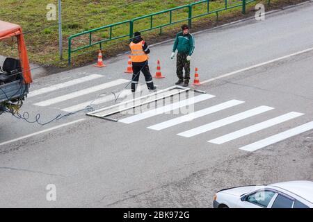 Applicazione della segnaletica orizzontale sull'asfalto con una macchina speciale. Editoriale Foto Stock