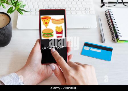 Donna usa lo smartphone per ordinare fast food con l'app per la consegna degli alimenti. Oder alimentare online concept. Foto Stock