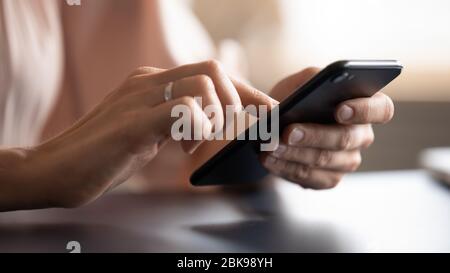 Chiudi le mani femminili che tengono il telefono, digitando sullo schermo Foto Stock