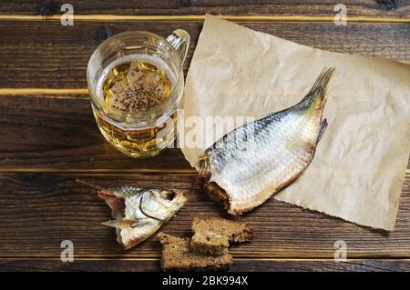 Bicchiere di birra e pesce secco salato su tavola di legno Foto Stock