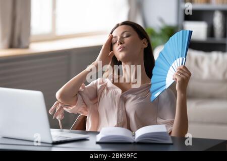 Donna surriscaldata che agita ventilatore, toccando fronte, soffrendo di riscaldamento Foto Stock