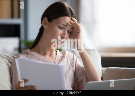Donna sconvolto lettura cattive notizie in lettera, controllo fatture Foto Stock