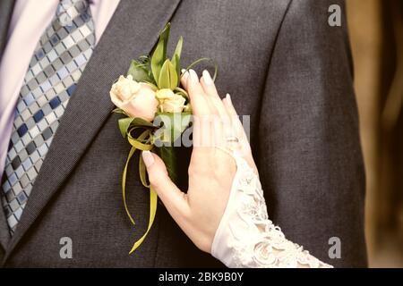 Appendere una sposa boutonniere di regolazione sulla camicia di sposi Foto Stock