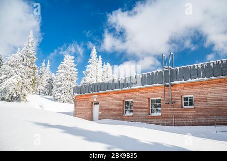 Capanna di legno coperta di neve in montagna, bel tempo. Foto Stock