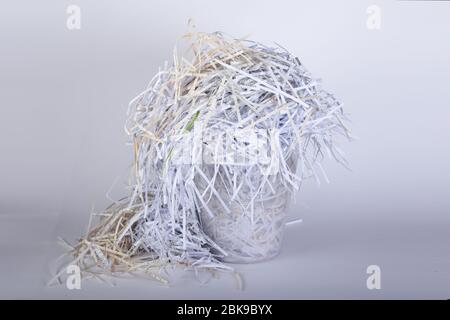 carta triturato con un tritadocumenti in un cestino di carta di scarto, sfondo bianco Foto Stock