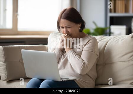 Donna triste e matura che guarda lo schermo del notebook e piange Foto Stock