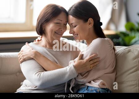 Felice madre più anziana e figlia adulta abbracciare, godendo momento tenero Foto Stock