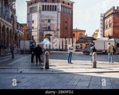 Cremona, Lombardia, Italia - 2 maggio 2020 - coda di persone per accedere al mercato alimentare aperto , accesso controllato da ufficio di polizia che esegue la scansione per il test della febbre Foto Stock