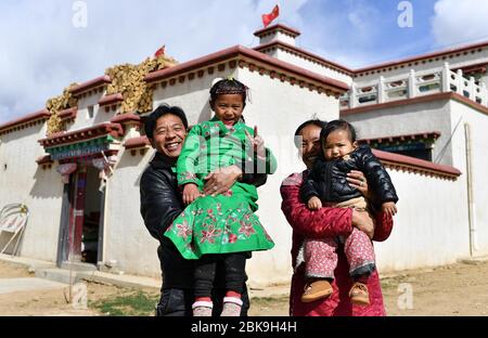 (200503) -- PECHINO, 3 maggio 2020 (Xinhua) -- Nijia (i L) e i suoi familiari posano per una foto di fronte alla loro casa presso l'insediamento di rilocazione Rongma a Gurum Township di Lhasa, capitale della regione autonoma del Tibet della Cina sudoccidentale, 2 aprile 2020. Nel 2018, più di 1,000 pastori si trasferirono dal prateria di Qiangtang con un'altitudine media di circa 5,000 metri nella cittadina di Rongma di Nagqu City all'insediamento di Rongma, 30 chilometri a ovest di Lhasa, grazie alla politica locale sulla riduzione della povertà. Questa misura consente anche di vivere animali selvatici al Qiangtang Nat Foto Stock