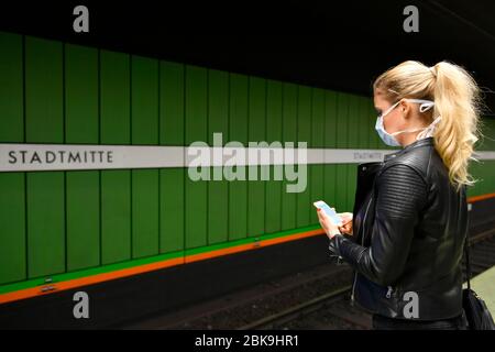 Donna con maschera facciale, sul telefono cellulare, in attesa di treno, S-Bahn, stazione Stadtmitte, Corona crisi, Stoccarda, Baden-Wuerttemberg, Germania Foto Stock