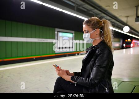 Donna con maschera facciale, sul telefono cellulare, in attesa di treno, S-Bahn, stazione Stadtmitte, Corona crisi, Stoccarda, Baden-Wuerttemberg, Germania Foto Stock