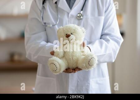 Vecchio pediatra maschile che tiene orso in mano, primo piano Foto Stock
