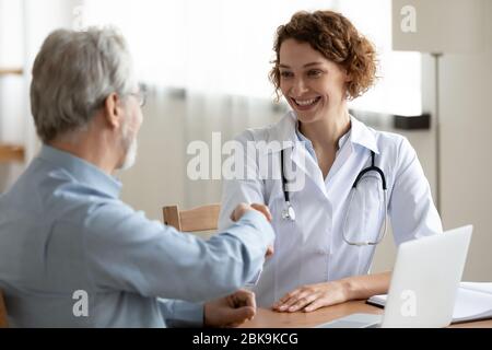 Sorridente medico femmina handshaking saluto sano paziente maschile senior Foto Stock