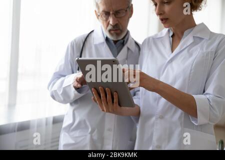 Due medici seri che discutono di dati utilizzando un tablet digitale Foto Stock