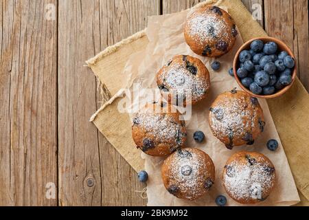 Muffin al mirtillo, vista dall'alto, spazio per le copie. Cupcake con frutti di bosco su vecchio tavolo rustico in legno Foto Stock