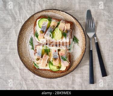 Aringa smorrebrod - tradizionali panini danesi. Pane di segale nero con aringa Foto Stock