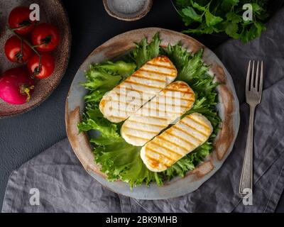 Halloumi alla griglia, formaggio fritto con insalata di lattuga. Dieta bilanciata su sfondo scuro, vista dall'alto Foto Stock