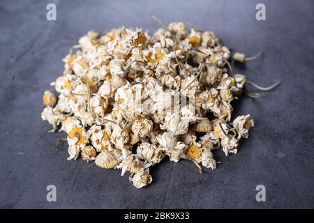 Tè alla camomilla essiccato su pietra, fondo in cemento. herbals secco, organico, sano e rilassante. Foto Stock