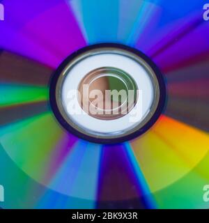Compact disc. Tenere un CD nelle mani. Il retro del CD riflette luci colorate. Colori arcobaleno. Foto Stock
