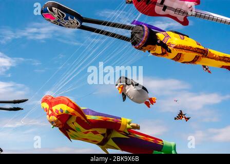 I giganti e colorati aquiloni volanti riempiono il cielo blu estivo al Southsea Kite Festival, Portsmouth, Regno Unito Foto Stock