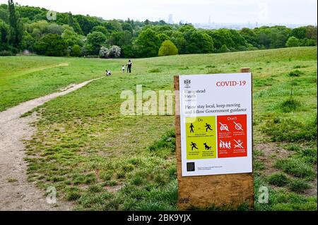 Hampstead Heath e London skyline, con istruzioni illustrate durante la pandemia di Covid-19. La gente cammina e corre osservando le distanze sociali. Foto Stock