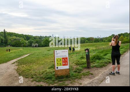 Hampstead Heath e London skyline, con istruzioni illustrate durante la pandemia di Covid-19. La gente cammina e corre osservando le distanze sociali. Foto Stock