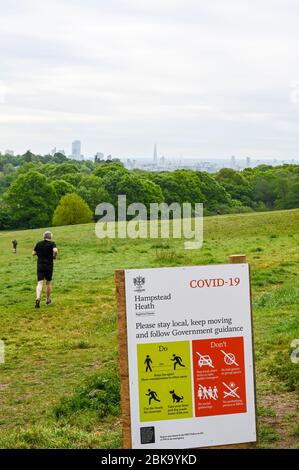 Hampstead Heath e London skyline, con istruzioni illustrate durante la pandemia di Covid-19. La gente cammina e corre osservando le distanze sociali. Foto Stock