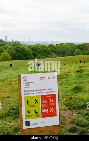 Hampstead Heath e London skyline, con istruzioni illustrate durante la pandemia di Covid-19. La gente cammina e corre osservando le distanze sociali. Foto Stock