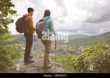 Giovane coppia in piedi sul bordo e fissando le montagne. Immagine a toni. Foto Stock