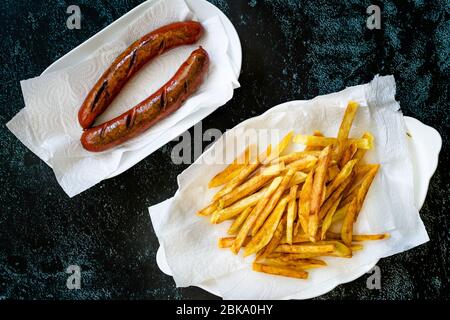 Salsiccia fatta in casa con patate Skinny French Fries in piatto e asciugamano di carta anche chiamato Peruvian Salchipapa. Fast food. Foto Stock