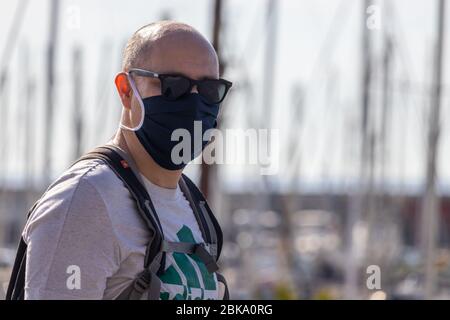 Barcellona, Spagna. 3 maggio 2020. Uomo che copre il viso con maschera di protezione e occhiali da sole nel porto di Barcellona al momento di Covid Lockdown Foto Stock