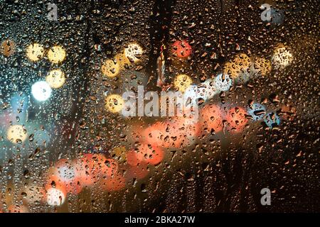 gocce di pioggia sul vetro, sullo sfondo della strada notturna Foto Stock