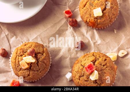 Muffin di banana appena sfornati con frutta candita posati su carta riciclata. Colazione al mattino, vista dall'alto Foto Stock