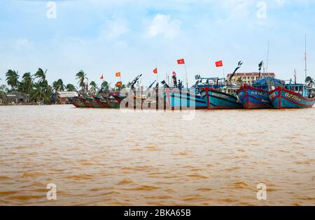 Hoi An Vietnam Ottobre 18 2013; Fiume scena con fila di diverse tradizionali barche da pesca vietnamite ormeggiate insieme con bandiere Foto Stock