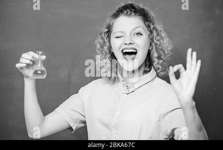 Saggezza. Felice studente con bicchiere. Risultati della ricerca chimica. Scienziato presso il laboratorio scolastico. Lezione scolastica. Esperimento biologico. Formula campione. Ragazza tenere il pallone chimico con liquido. OK gesto. Foto Stock