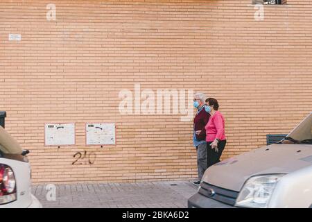 Valencia, Spagna, 02 maggio 2020: Coppia anziana contro muro di mattoni, indossando maschere mediche durante la loro passeggiata. Covid-19 o infezione da coronavirus p Foto Stock