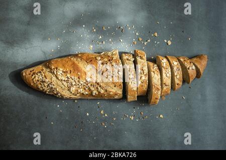 Pane appena sfornato e affettato con crostini su fondo in cemento. Cibo sano, delizioso e fatto in casa. Vista dall'alto, disposizione piatta. Foto Stock